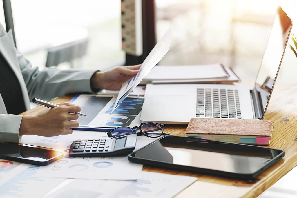 „Arbeitsplatz mit Laptop, Finanzunterlagen, Diagrammen und Taschenrechner – kaufmännische Planung bei Kramke“